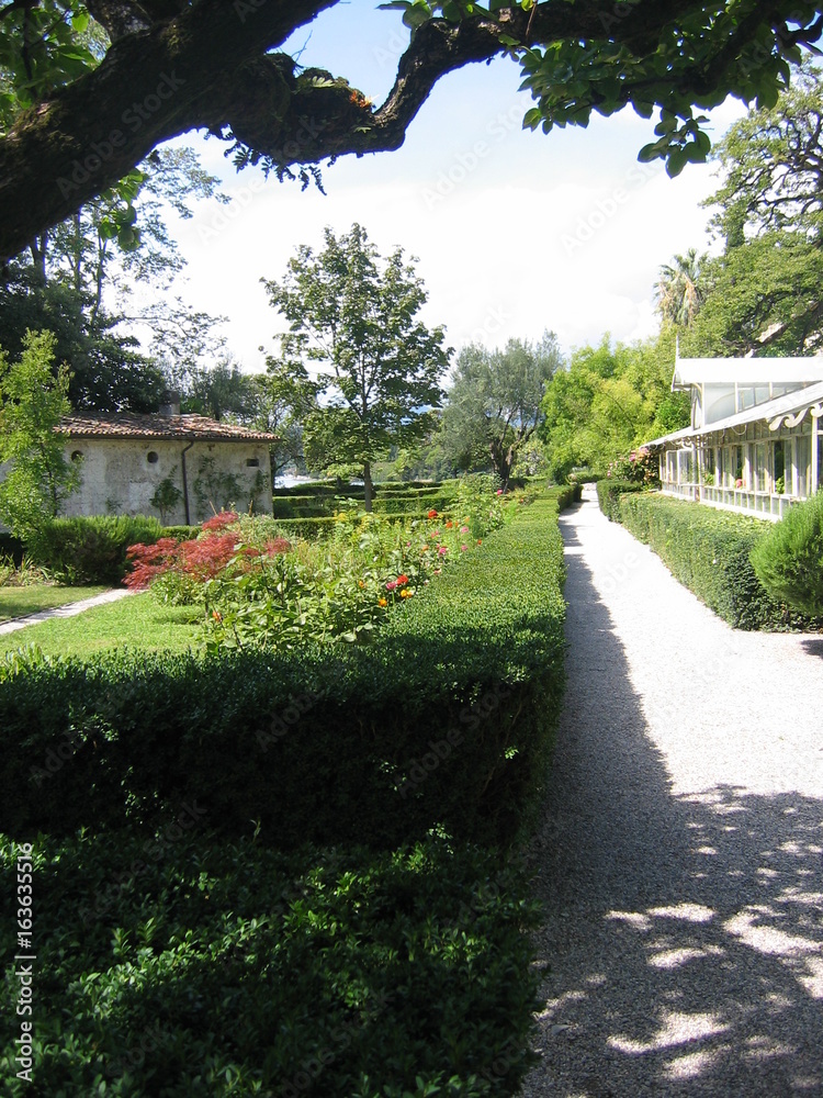 Fototapeta premium Un viale soleggiato che attraversa il giardino di un castello in nord italia