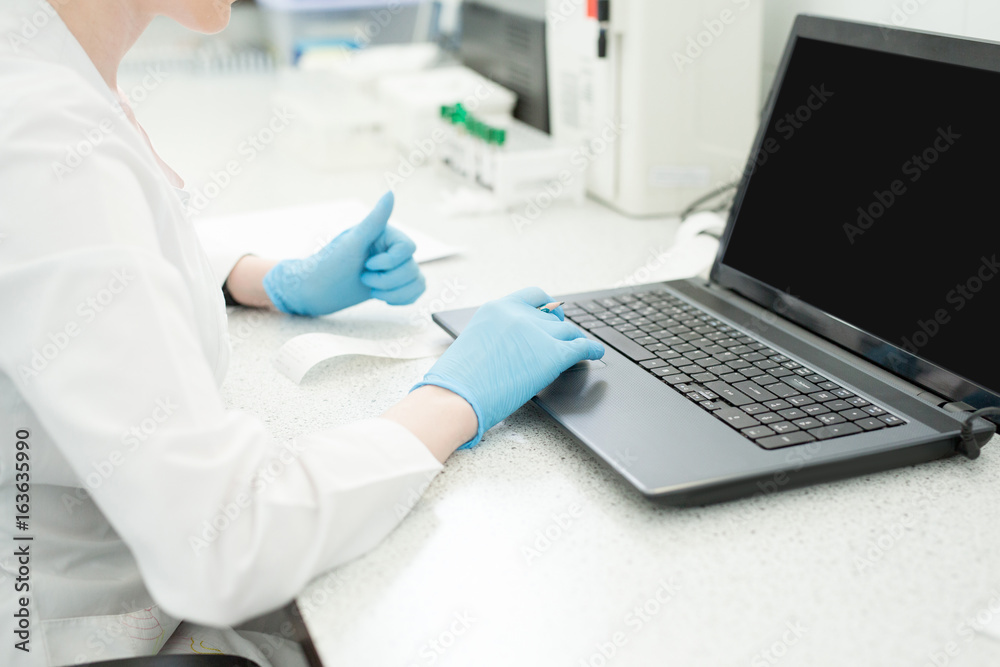 Modern technology in science. Scientist entering data of analysis results to laptop at laboratory Modern technology in science. Scientist entering data of analysis results to laptop at laboratory