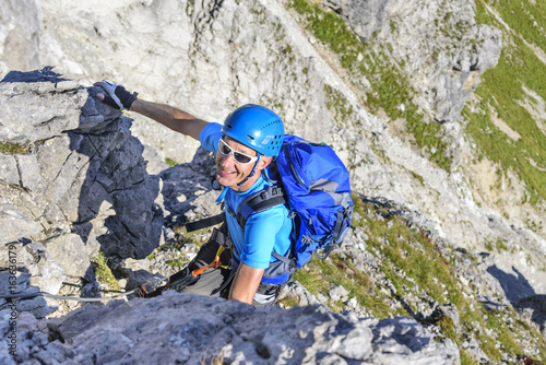 Mann klettert gutgelaunt im Klettersteig