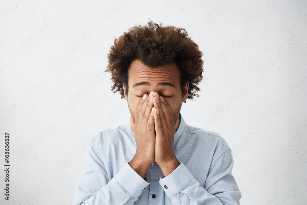 Φωτογραφία Desperate male with bushy dark hair covering his face with hands closing eyes being tired and frustrated wanting to sleep having some troubles in his personal life