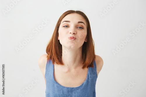 Portrait of cheerful young beautiful pretty girl looking at camera sending kiss over white background.
