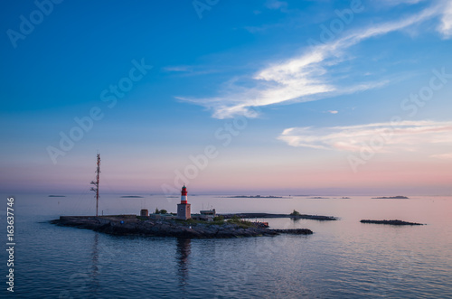 Pink sunset over the small island with a lighthouse near Helsinki Finland © Gennady Kurushin