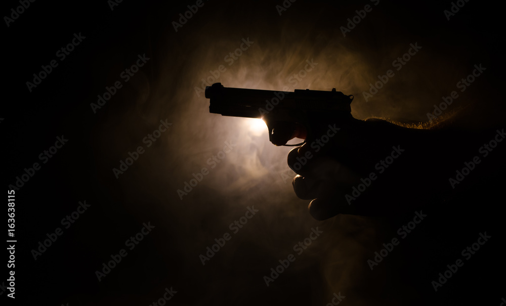 Male hand holding gun on black background with smoke ( yellow orange red  white ) colored back lights, Mafia killer concept Stock Photo | Adobe Stock