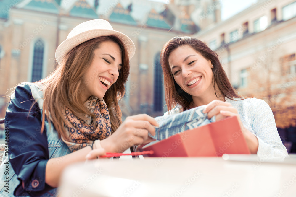 Happy shopaholic women checking clothes at cafe.