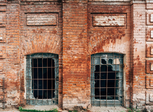 Facade of old red brick house with broken glass