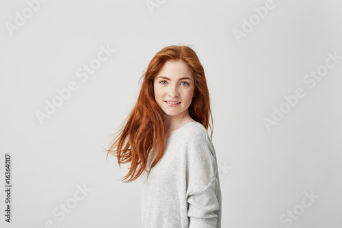 Portrait of young pretty girl with beautiful foxy hair looking at camera smiling over white background.
