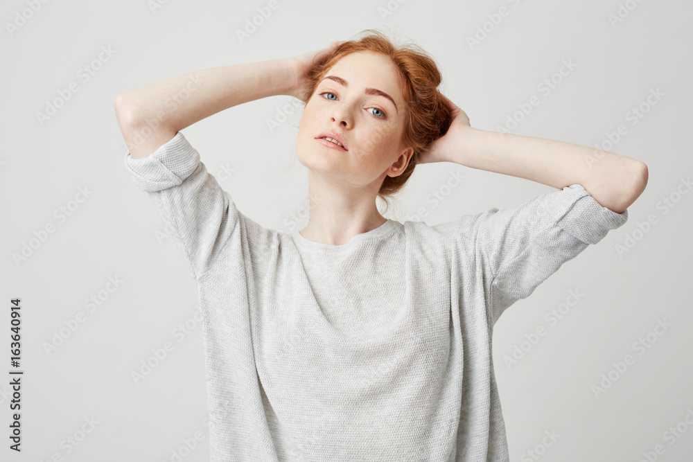 Portrait of young beautiful redhead girl with hands behind head smiling looking at camera over white background. Portrait of young beautiful redhead girl with hands behind head smiling looking at camera over white background.