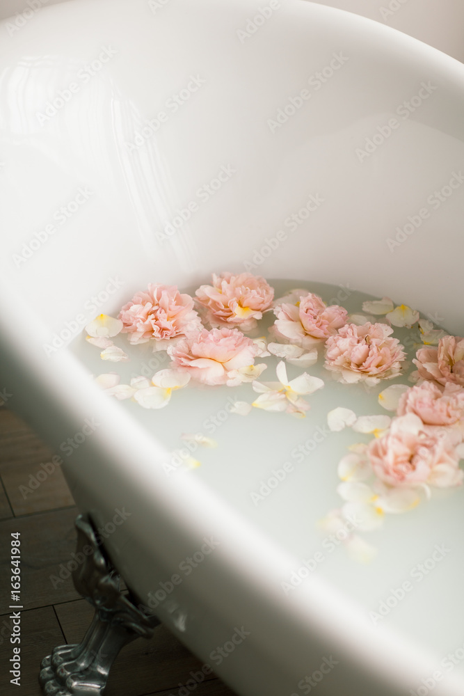 White bath with milk and rose petals. Relaxation and harmony