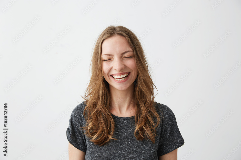 Young cheerful happy girl smiling laughing with closed eyes over white background.
