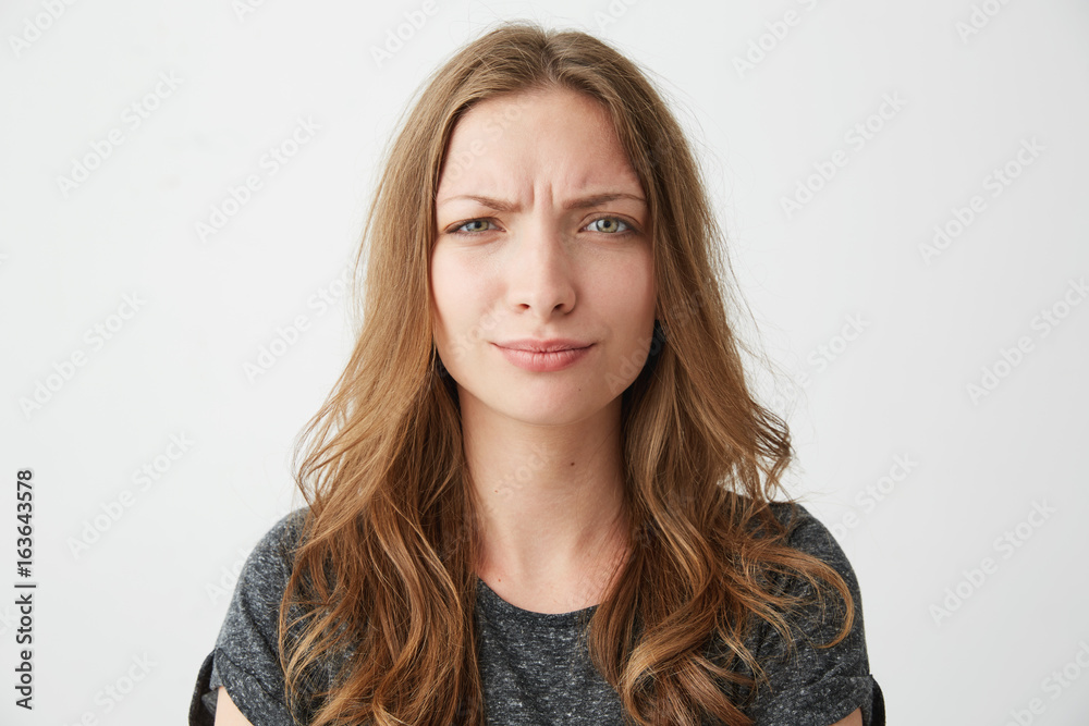 Portrait of displeased young pretty girl looking at camera with contempt over white background. Portrait of displeased young pretty girl looking at camera with contempt over white background.