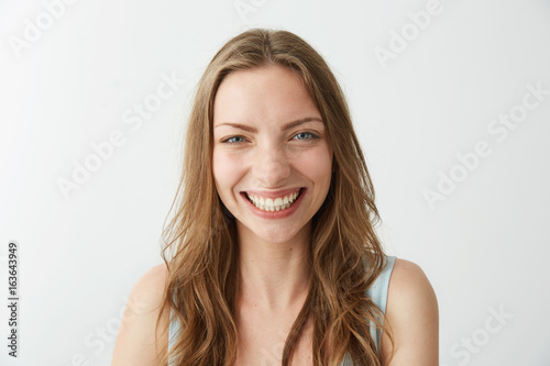 Beautiful sincere happy girl smiling laughing looking at camera over white background.
