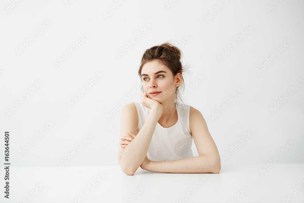 Dreamy young beautiful girl student sitting at table dreaming thinking over white background. Dreamy young beautiful girl student sitting at table dreaming thinking over white background.