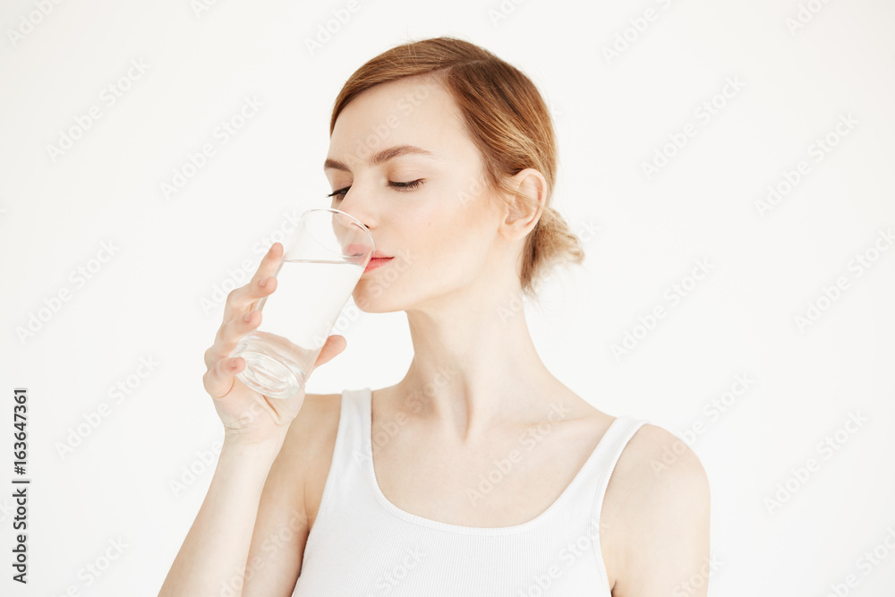 Young beautiful girl with perfect skin drinking water over white background. Beauty and health lifestyle. Facial treatment. Young beautiful girl with perfect skin drinking water over white background. Beauty and health lifestyle. Facial treatment.