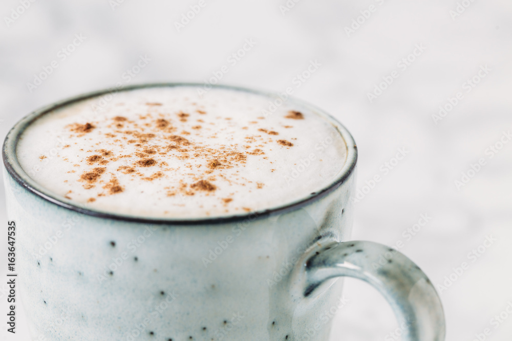 Cappuccino in a rustic style mug on a marble table Cappuccino in a rustic style mug on a marble table