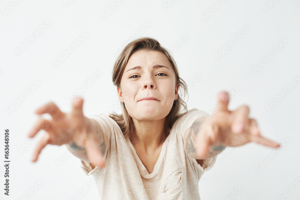 Young funny pretty girl stretching hands to camera over white background. Young funny pretty girl stretching hands to camera over white background.