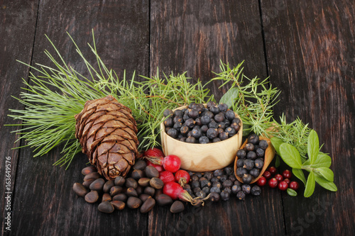 juniper berries, cedar cone and dog rose berries on wooden background