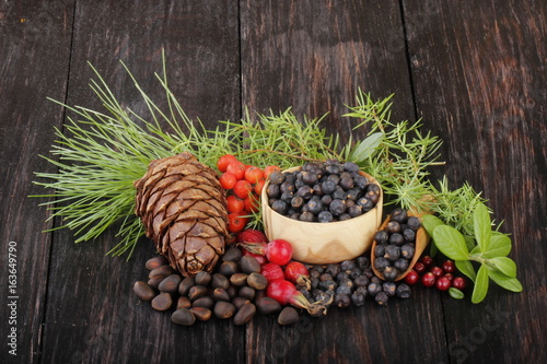 juniper berries, cedar cone and dog rose berries on wooden background photo