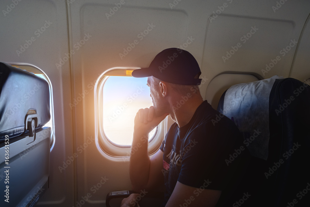 Obraz premium A man looks out the window of a porthole in an airplane