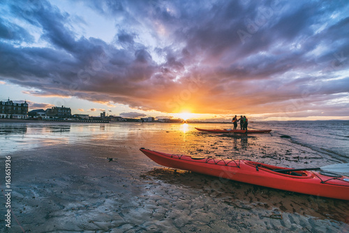 Kayaks and kayakers on beach at sunset. Portobello, Edinburgh, Scotland, UK