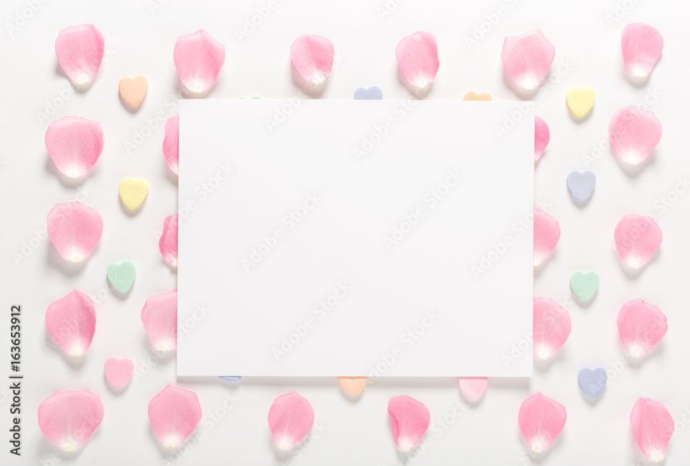 Rose petals and blank white message card aligned on a white background Rose petals and blank white message card aligned on a white background