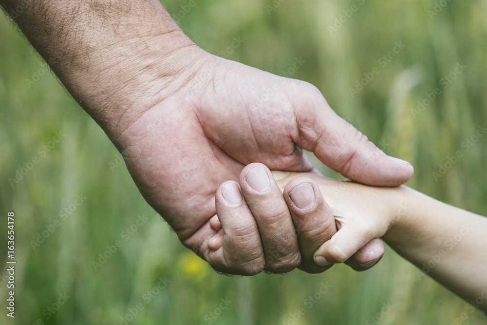 Hands closeup of a small child and an elderly person to stay together Hands closeup of a small child and an elderly person to stay together