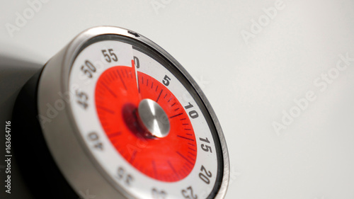 Classical vintage kitchen countdown timer close up shot with analog clock face and red remaining time display, 60 minutes left, low depth-of-field with blur