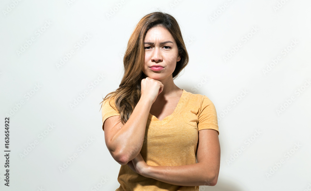 Young woman in a thoughtful pose on a off white background Young woman in a thoughtful pose on a off white background