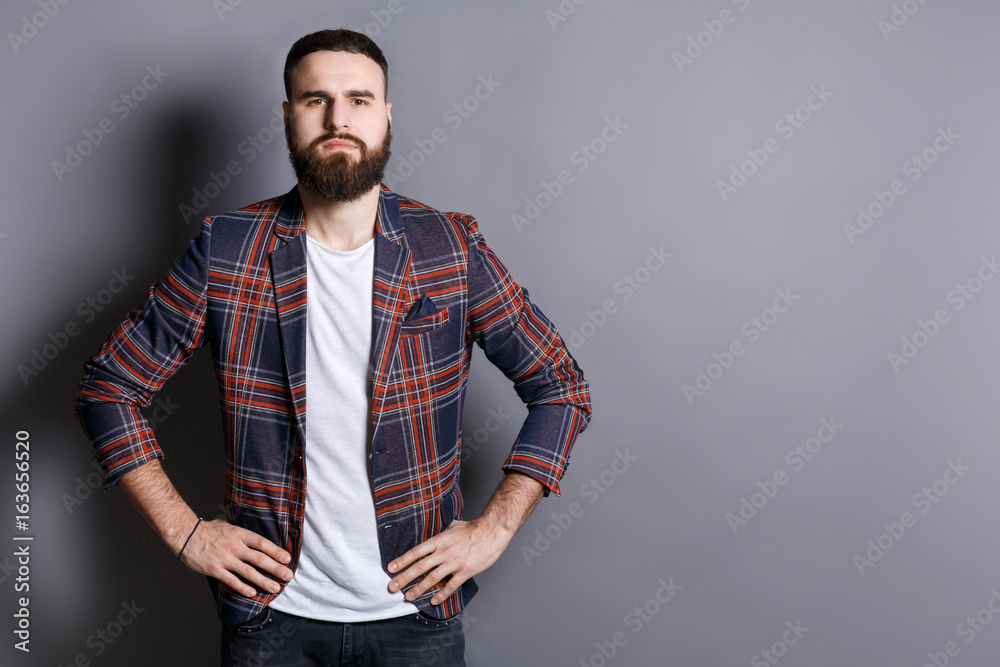 Serious bearded man posing with hands on hips