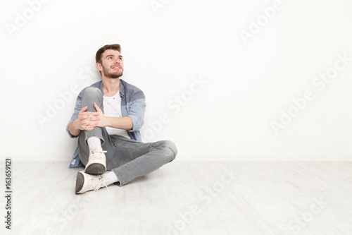 Pensive man sitting on floor and looking upwards