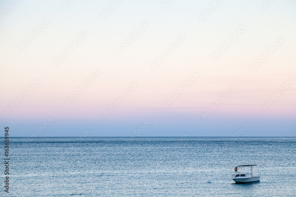 boat in sea in blue and pink summer twilight