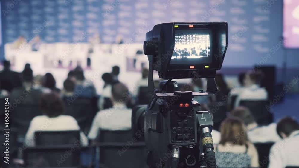 videocamera keeps record of performance of lecturer in presentation hall. videocamera keeps record of performance of lecturer in presentation hall.