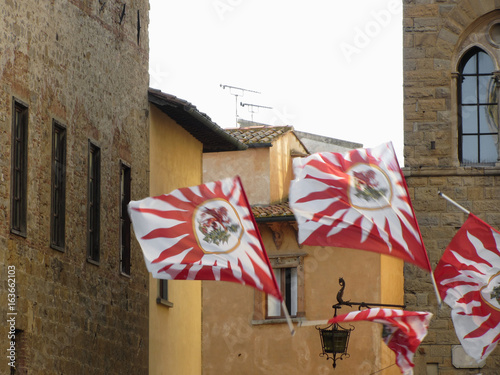 Fluttering flags in Volterra village during historic flag throwing competition . Tuscany, Italy