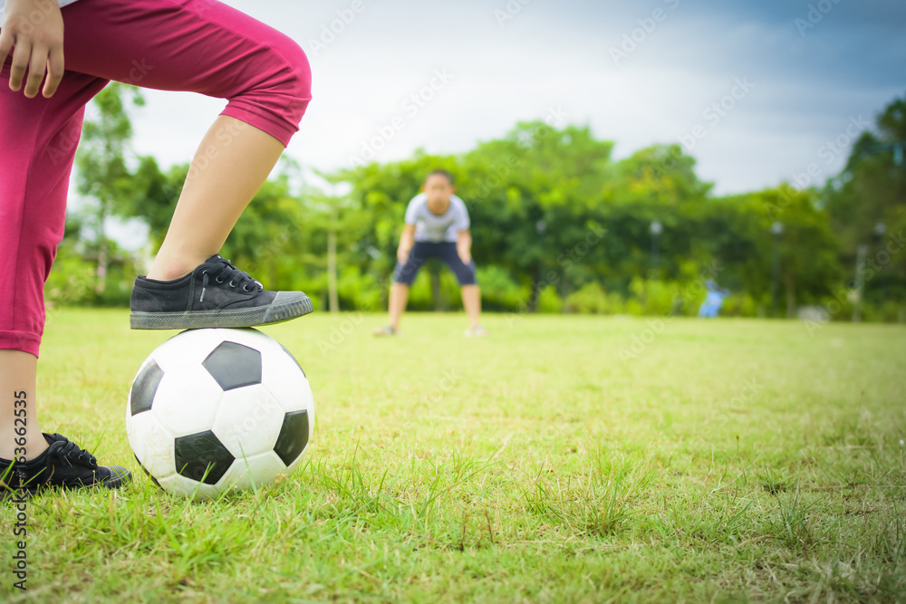 Boy playing football with brother in the park