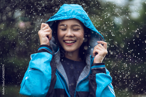 Foto Asian woman wearing a raincoat outdoors. She is happy.