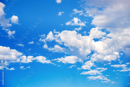 white clouds on a blue sky. Delicate fluffy white clouds in the sunlight against a blue sky. Spring seamless summer background. Template for design. Light,