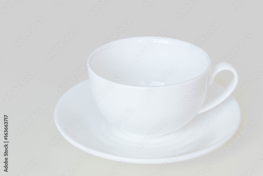 White cup and saucer for tea or coffee isolated on a light background. White cup and saucer for tea or coffee isolated on a light background.