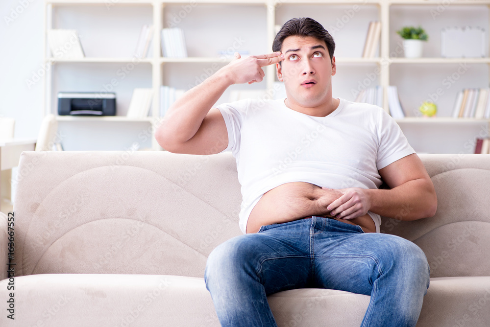 Fototapeta premium Man suffering from extra weight in diet concept