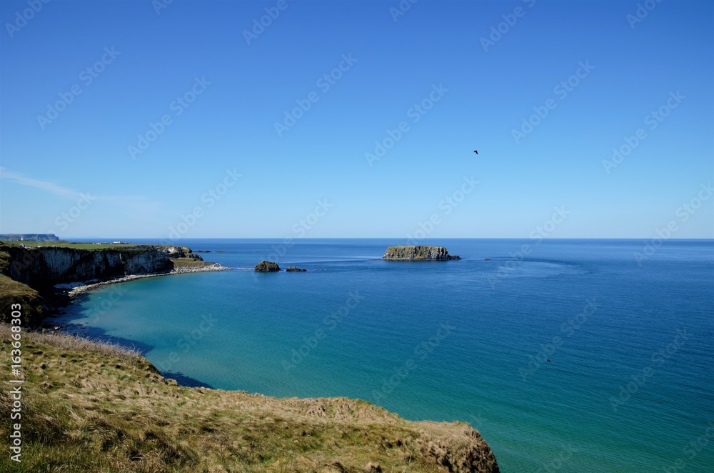 Long shot over the coastline at the Carrick-a-Rede coastal walk to the rope bridge in County Antrim, Northern Ireland, UK