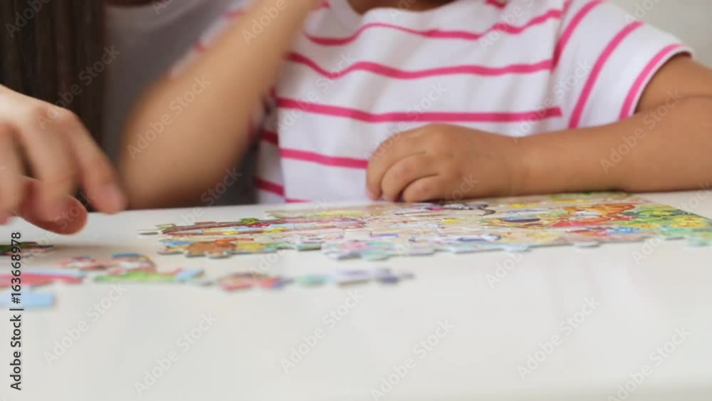 Mother and daughter doing a puzzle together in the light living room Mother and daughter doing a puzzle together in the light living room