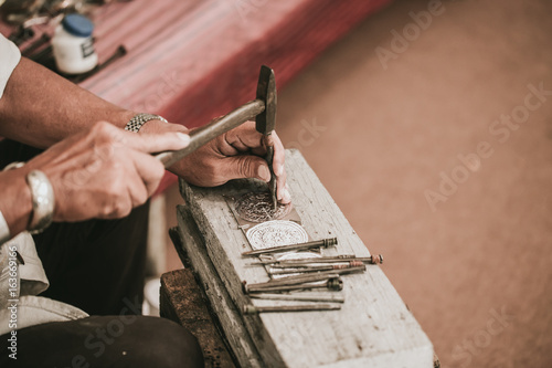 North Thai senior artist handcraft carver silver with hammer and chisel for culture style silver art craft at Chiang Mai, Thailand.