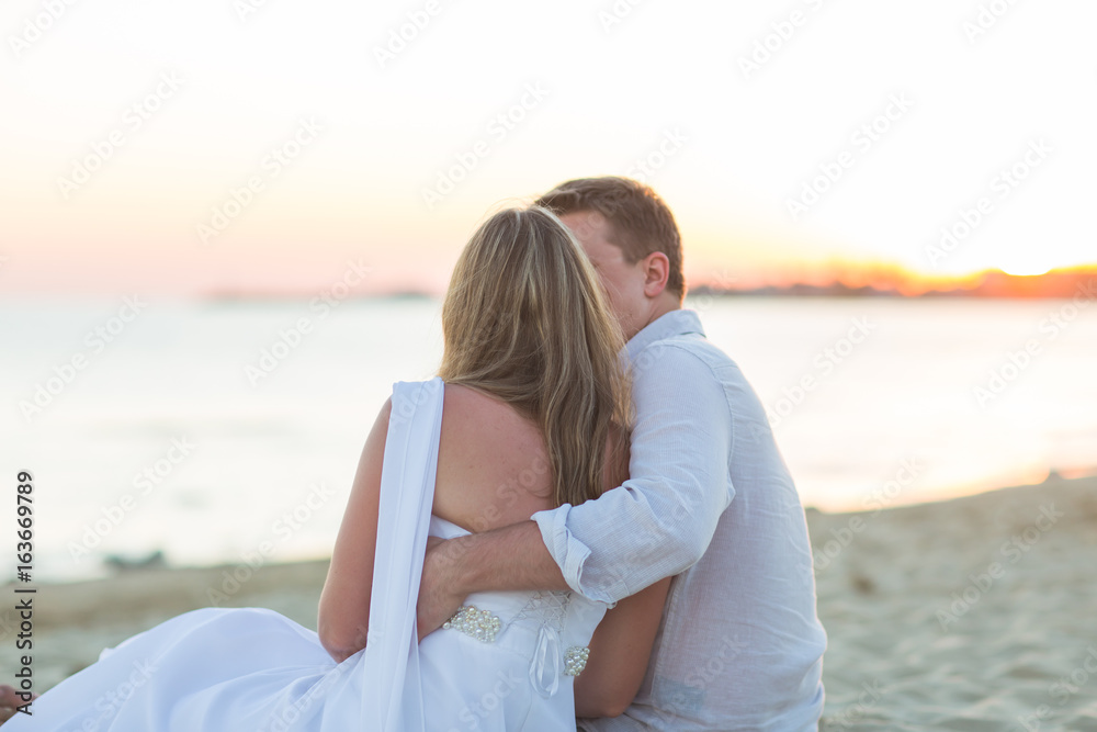 Young love couple sitting together on beach