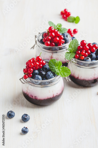 Italian dessert panna cotta with berry sauce in glass jars