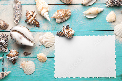 Marine summer postcard. Seashells on turquoise wooden boards in the sand on the beach