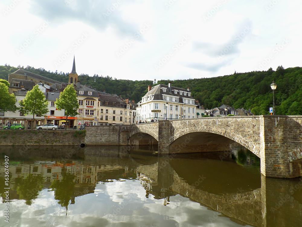 Reflections of the old stone bridge and the vintage buildings on Semois river at Bouillon, Belgium 