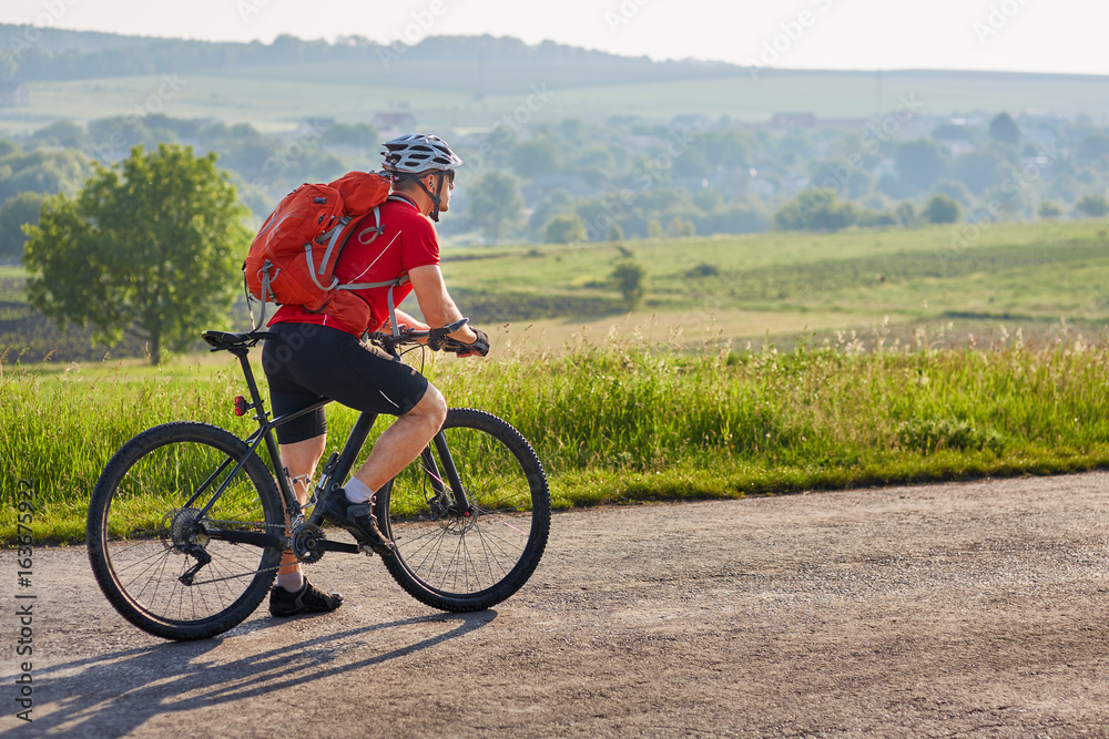 Potrtrait of the cyclist on a long road on the countryside against summer landscape. Potrtrait of the cyclist on a long road on the countryside against summer landscape.