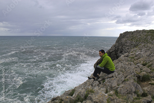 Guy looking at the sea to relax in a cliff, Spain