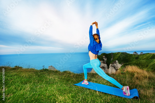 Sporty woman exercising on the top of cliffs photo