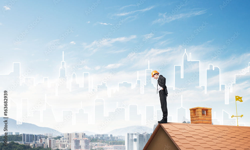 Engineer man standing on roof and looking down. Mixed media Engineer man standing on roof and looking down. Mixed media