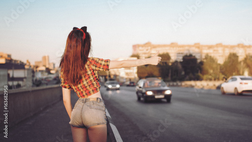 Young sexy brunette catches car photo