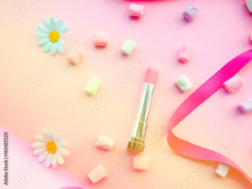 Fashion concept : Flat lay of pink cute woman bag lipstick, creams, honey, marshmallow, powder on colorful background with copy space